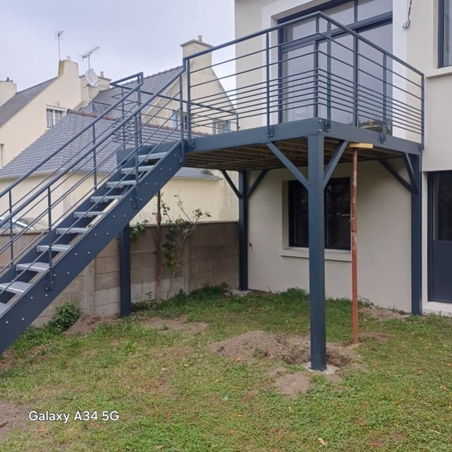 Terrasse suspendue en structure métallique avec escalier d'accès au jardin