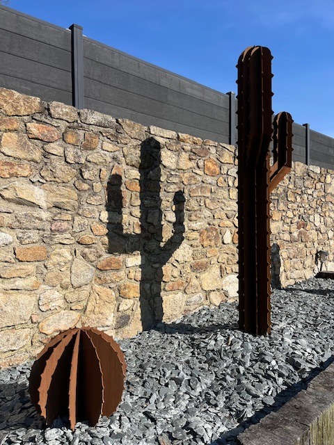 Sculpture de cactus en acier corten dans un parterre d'ardoises